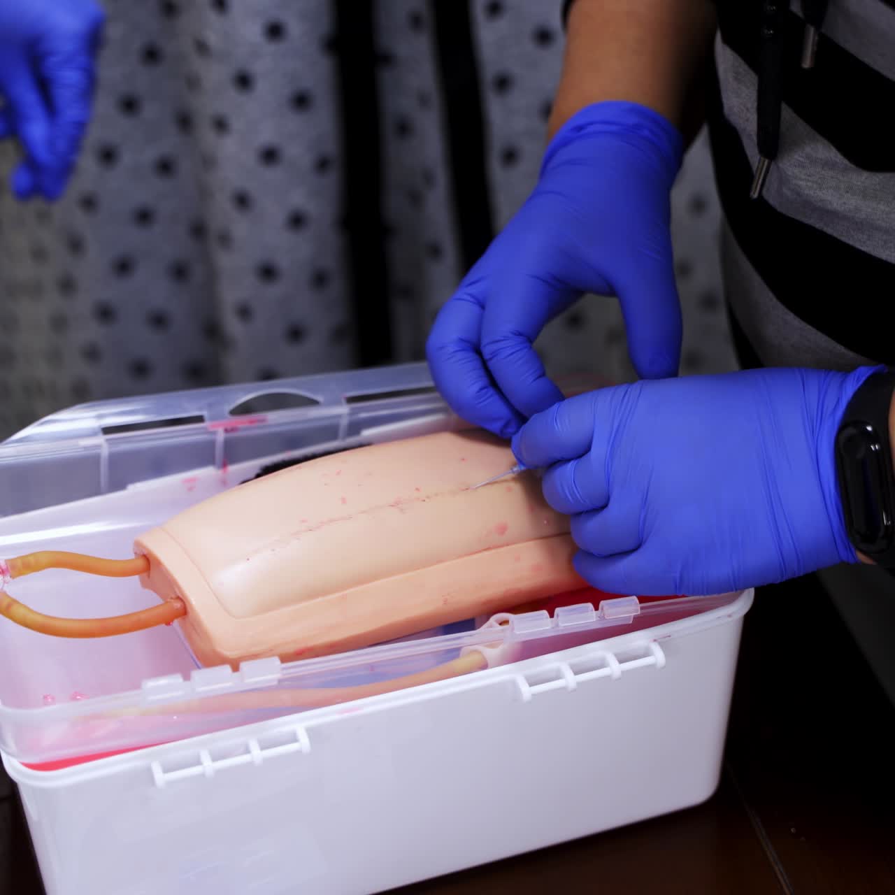 Hands in gloves making injection with a syringe for puncture. Simulation medical training model. Medical procedure concept, simulation medicine training