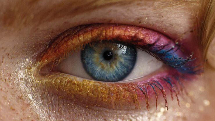 Close-up van een prachtige oogopslag met kleurrijke make-up met levendige blauwe, gouden en roze tinten, en gedetailleerde glitteraccenten