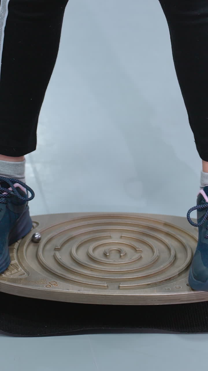 피트니스 세션 중에 런스 보드 위에 서 있는 스니커와 조을 입은 사람의 낮은 각도 관측, 개인은 안정성과 조정에 초점을 맞추고 있습니다.