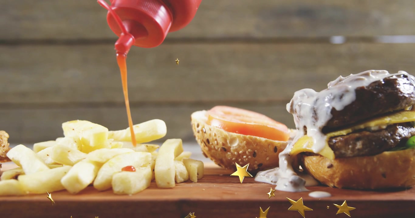 Bottiglia rossa a spremere che si ferma sopra, versando ketchup sulle patatine fritte mentre un hamburger gocciola, aggiungendo un bagliore promozionale.