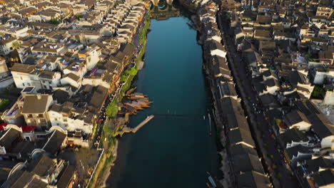 Drone-shot-tilting-over-the-Tuo-Jiang-river-and-the-Phoenix-Hong-Bridge,-in-sunny-Fenghuang-County,-China