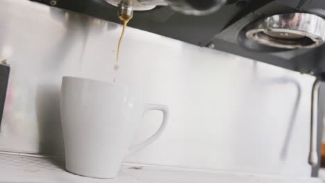 primer plano de la máquina de café en funcionamiento vertiendo café fresco en la taza en la cafetería