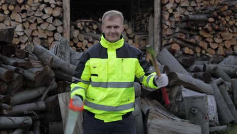 lumberjack in reflective jacket. man woodcutter holds small axe and saw on his hands. firewood