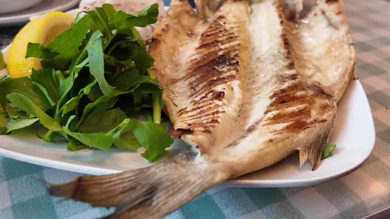 Appetitlicher gegrillter Fisch, serviert mit Zitrone und frischem Salat.