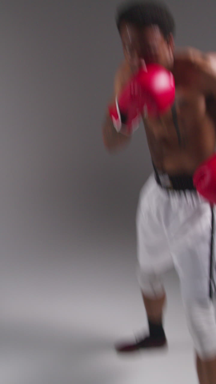 video vertical en tiempo real de estudio pov disparo de boxeador masculino tatuado con guantes de boxeo en un partido de boxeo golpeando hacia la cámara 1