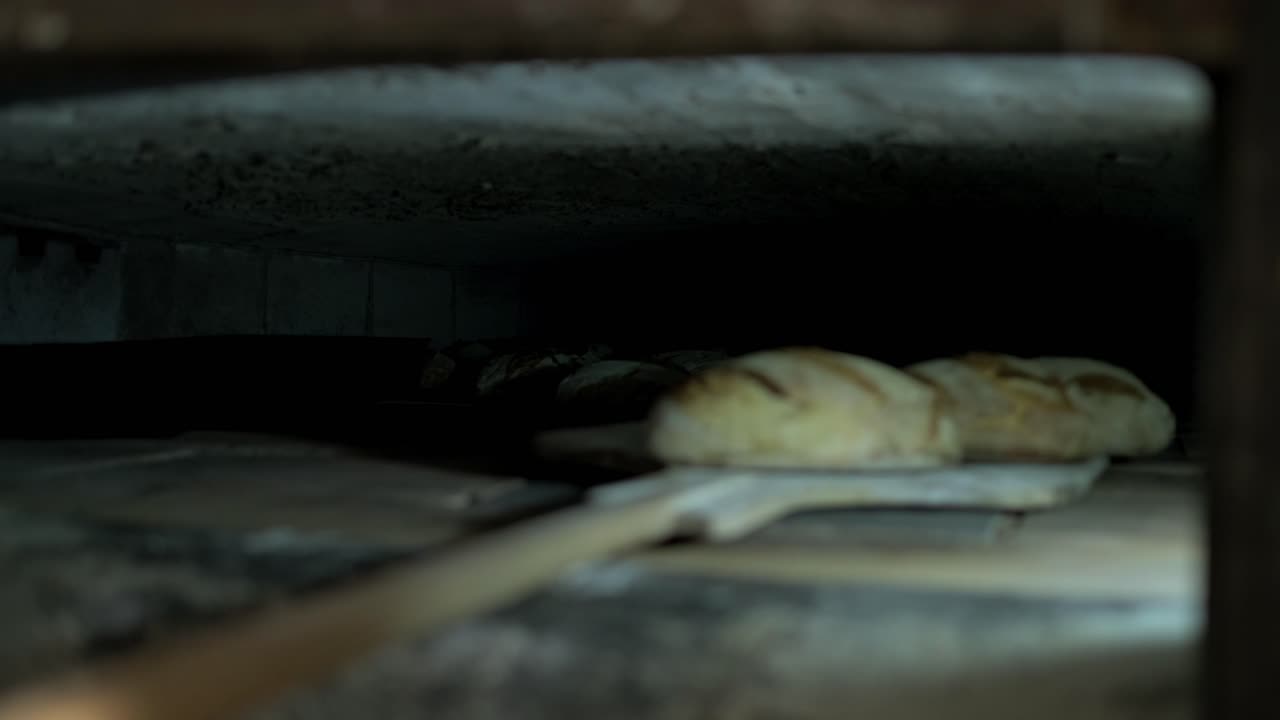 Shot of inside oven, baker’s peel going out with some crusty and goldy loaf bread