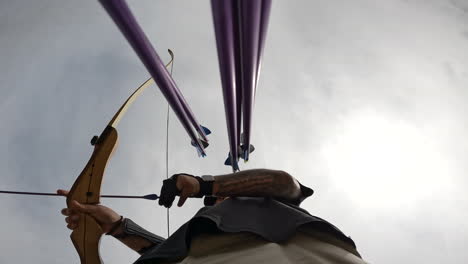 Toma-En-ángulo-Bajo-De-Un-Arquero-Recogiendo-Una-Flecha-Y-Luego-Disparándola-Desde-Un-Arco-En-Un-Campo-De-Tiro-Con-Arco