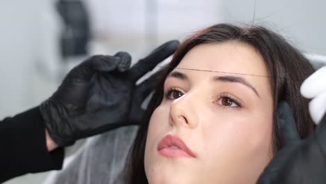 woman makeup artist during eyebrow correction procedure