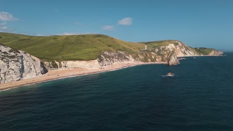 fast dolly right revealing white cliffs and lush green hills at durdle door