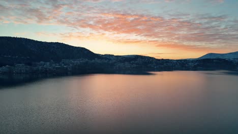 A-drone-shot-of-village-mountain,-warm-weather,-flying-above-a-dreamy-sunset-reflecting-water-lake,-4K-video,-European-spring-nature,-beautiful-landscape,-scenic-colorful-clouds