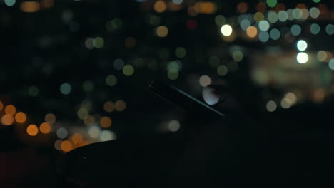 mujer con teléfono celular en el fondo de las luces de la ciudad por la noche