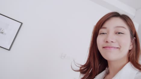 slow motion asian woman with white shirt talking to selfie video call walk to bed with a smile