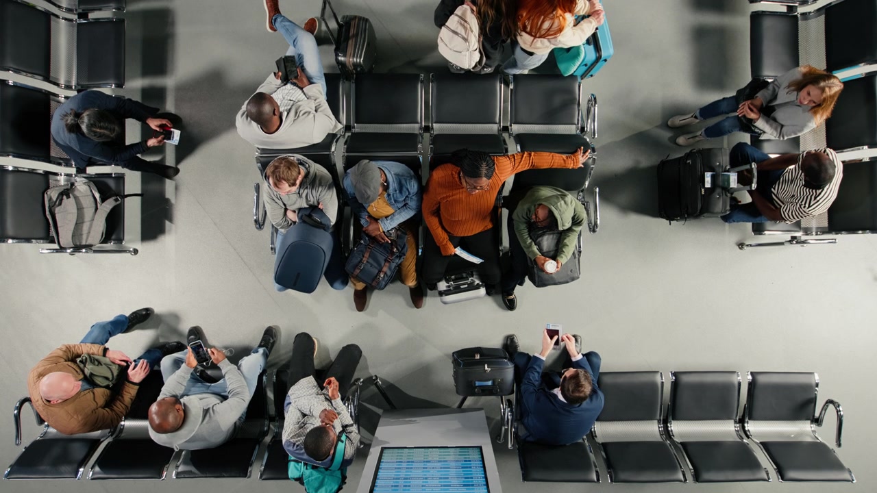 Group of passengers in airport terminal checking departure board for timetable