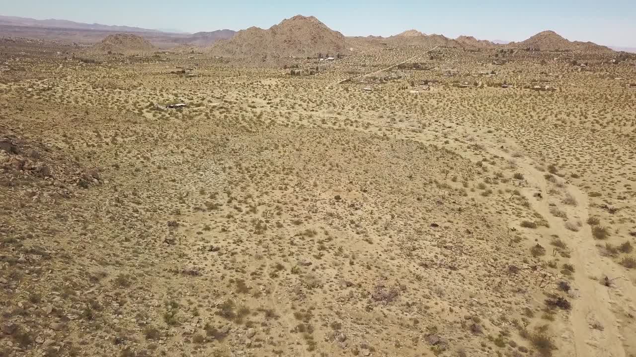 sobrevuelo aéreo desierto arenoso con montañas en segundo plano.