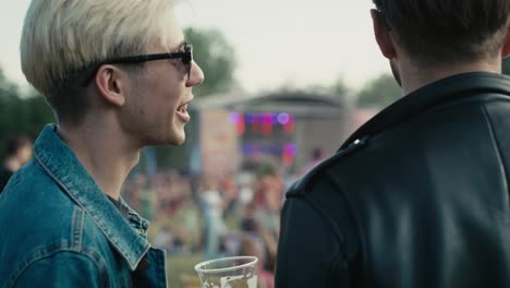 achteruitzicht van twee jonge blanke mannen die plezier hebben op een muziekfestival terwijl ze bier drinken