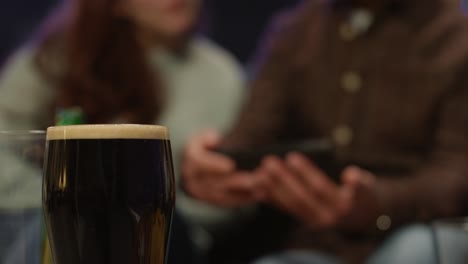 cerca de una pinta de cerveza con amigos en casa o en el bar celebrando en la fiesta del día de san patricio posando para una selfie en el fondo