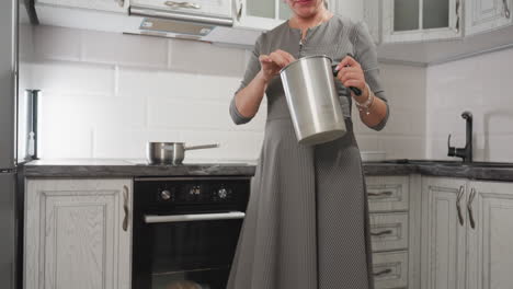 down to top view of elegant woman dancing while stirring flour mixture in metal container with focused expression in cozy kitchen, blending joy and concentration in cooking routine
