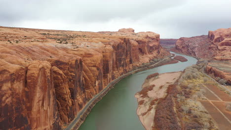 aerial view of colorado river canyon, steep sandstone cliffs and road to moab, utah usa - drone shot