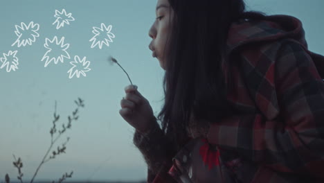 girl blowing dandelion in meadow at dusk, with drawn petals floating in air