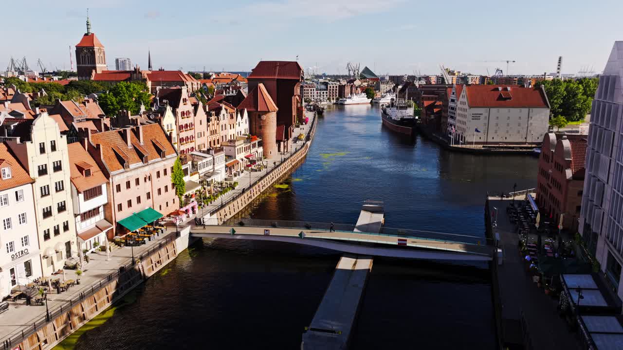 Drone footage shows Gdansk Old Town riverfront at sunrise with bridge view