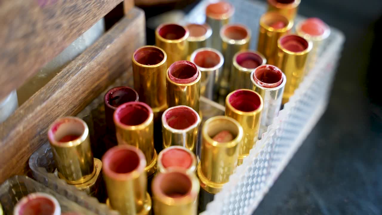 Close-up of assorted gold lipstick tubes in a clear organizer, showcasing various shades at a beauty parlor