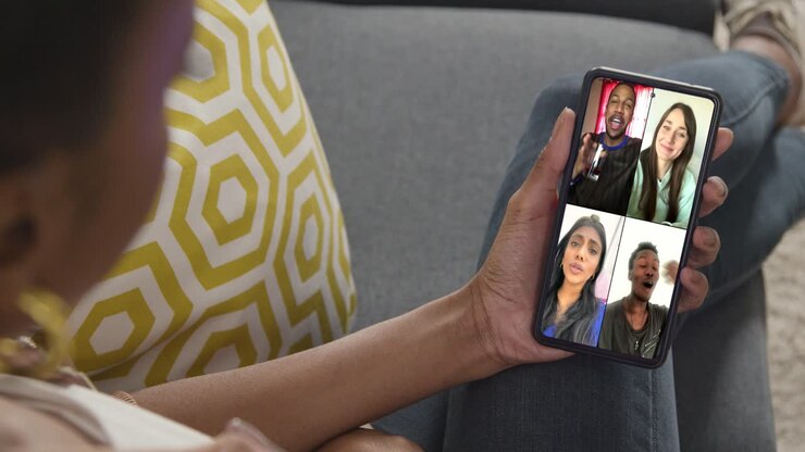 Close Up Of Woman Sitting On Sofa At Home Having Group Online Chat With Friends On Mobile Phone