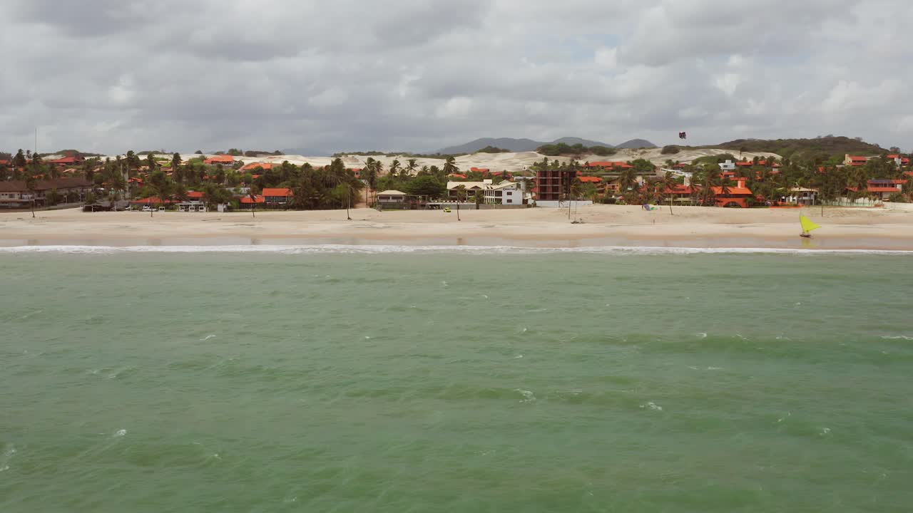 antena: cumbuco durante el día con gente haciendo kitesurf
