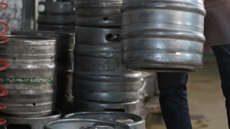 young brewer wearing a leather apron carries a barrel of craft beer at a modern brewery