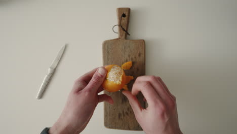 Peeling-A-Tangerine-with-hands-in-kitchen-4K-Top-Shot-POV