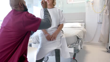 African-american-male-doctor-examining-face-of-caucasian-female-patient-at-hospital