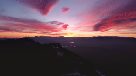 Silueta-Vista-Aérea-Volando-Lateralmente-Efecto-De-Paralaje-Durante-La-Increíble-Y-Colorida-Puesta-De-Sol-En-Invierno-Con-Nieve-En-Los-Picos-De-Las-Montañas-En-Madrid,-España