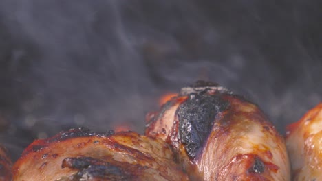 chicken drumsticks close up with flames out of focus in background with details on crispy slightly charred skin. lean high protein bbq outdoor summer food, juice, delicious and tasty.
