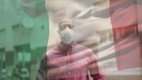 Animation-of-flag-of-italy-waving-over-man-wearing-face-mask-during-covid-19-pandemic