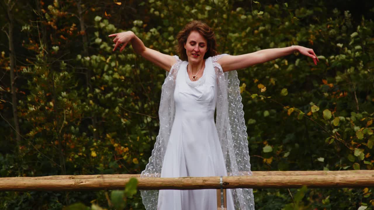 Belle femme en longue robe élégante dansant au ralenti sur un pont panoramique