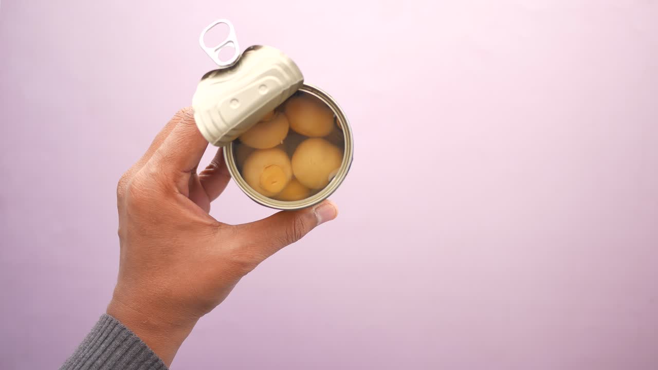 Hand Holding an Open Can of Canned Eggs