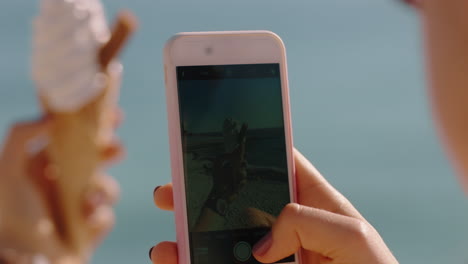 close up hand woman taking photo of ice cream using smartphone enjoying summer vacation eating soft serve on beach sharing experience