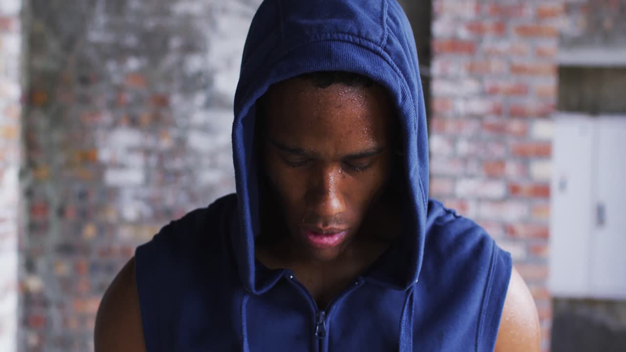 허디를 입은 아프리카계 미국인 남자의 초상화 운동 후  ⁇ 을 흘리며 도시 b에서 카메라를 보고 있습니다.