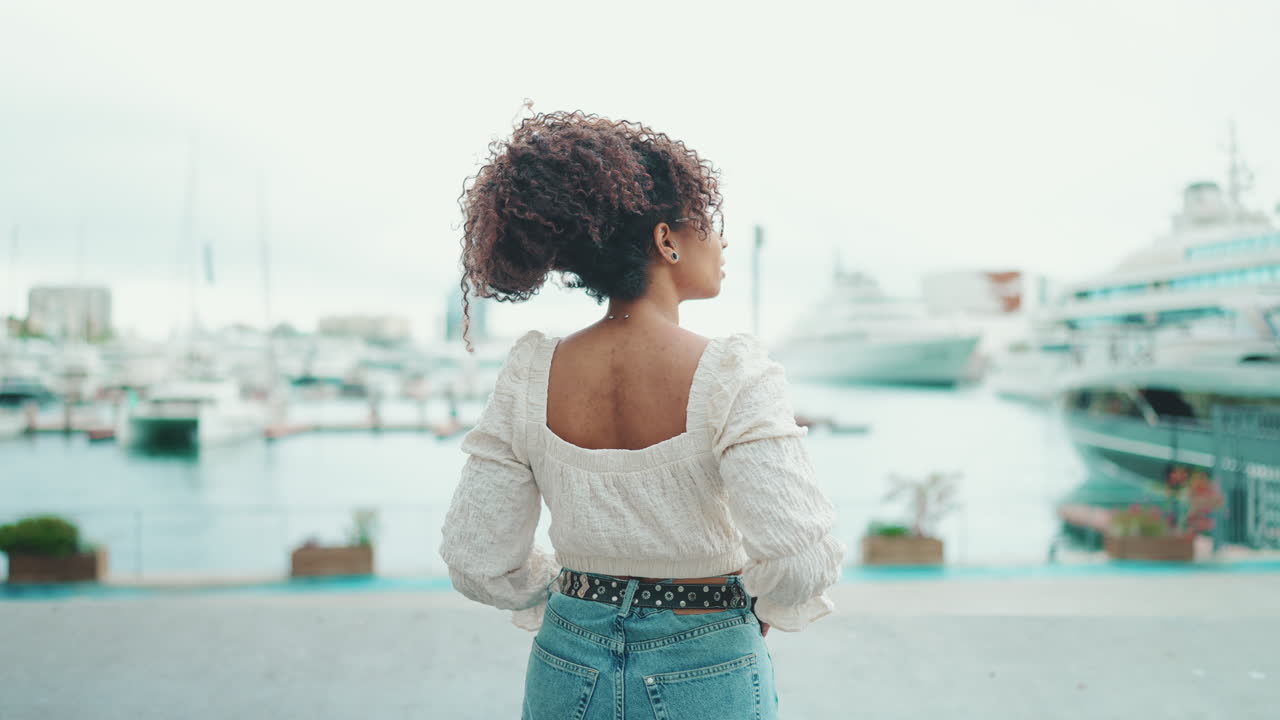 Woman with curly hair looking at yachts in a marina