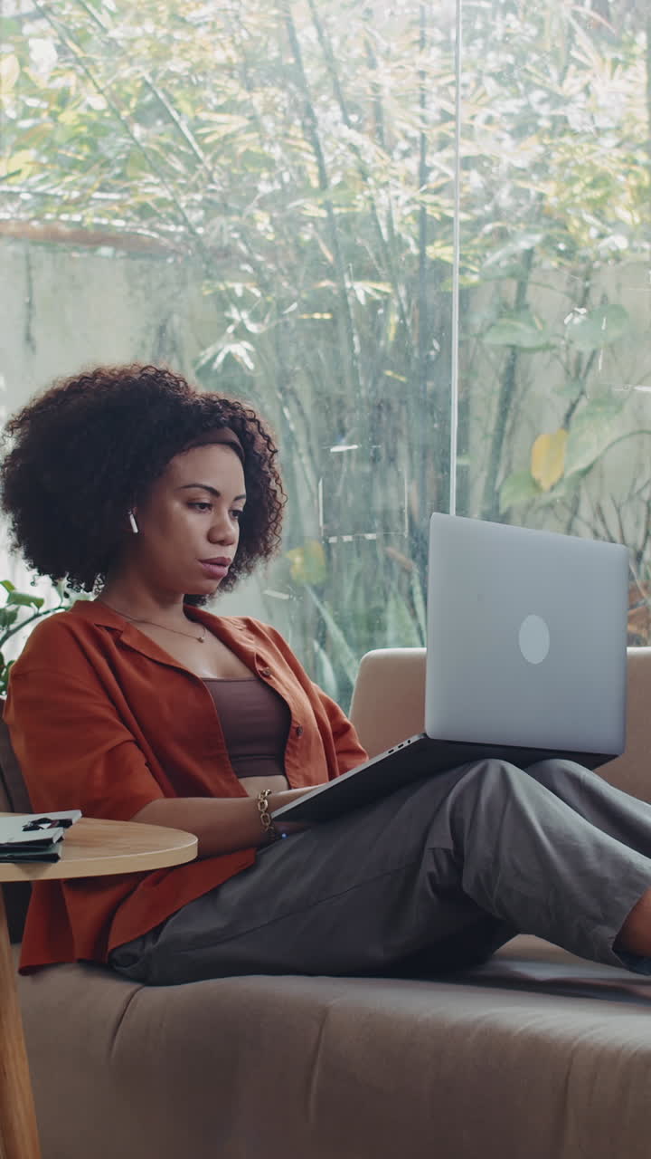 Latin Businesswoman Doing Report on Laptop and Drinking Tea on Sofa