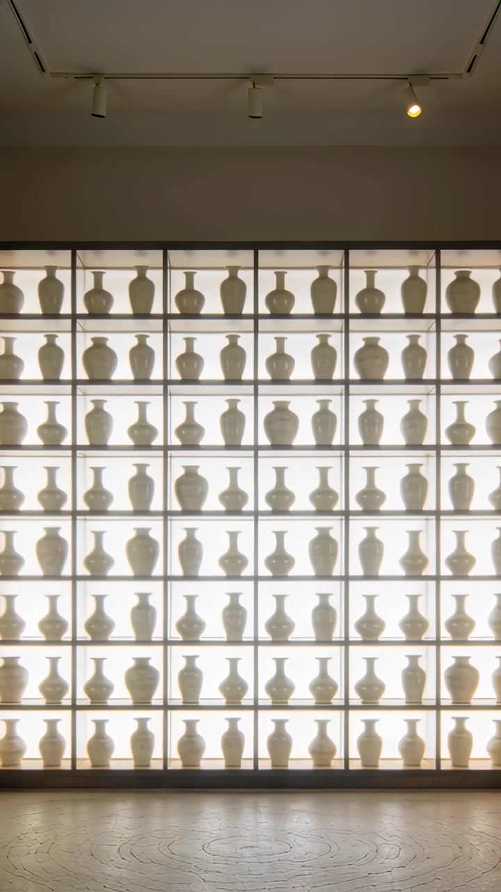 Vertical video: Center framing causing camera pulling back, revealing backlit vase grid at gallery