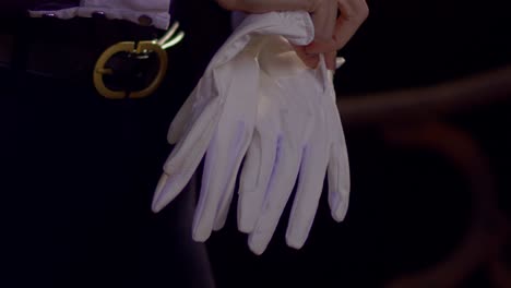 cinematic slow motion shot of woman putting on white horse riding gloves, close-up slomo