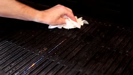 person meticulously cleaning a grill using a white cloth
