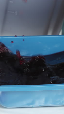 red liquid pouring into a blue container