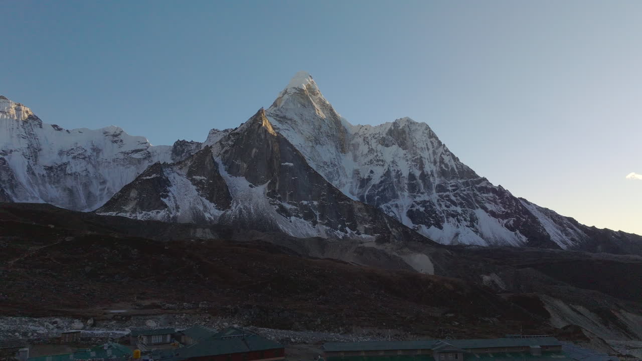 Ripresa aerea all'ora d'oro del tramonto sulla Valle di Chhukung nella regione dell'Everest in Nepal, che rivela il Monte Ama Dablam che si erge oltre il villaggio. Insediamento ad alta quota incorniciato dalle cime himalayane.