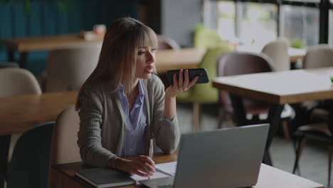 Asiatische-Frau-Spricht-Auf-Dem-Handy-Mit-Sprachassistent.-Eine-Frau,-Die-Auf-Der-Couch-Sitzt,-Führt-Telefongespräche-über-Die-Freisprecheinrichtung-Mit-Einem-Freund,-Führt-Eine-Spracherkennung-Durch-Oder-Nutzt-Internetdienste-über-Einen-Virtuellen-Assistenten