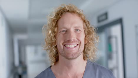 retrato de un feliz médico caucásico con el cabello rizado, sonriente, en cámara lenta