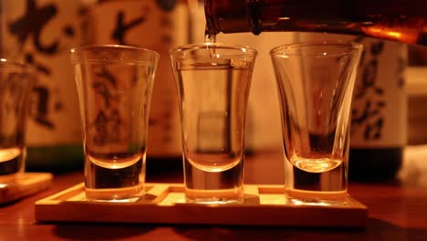 sake being poured into three glasses evenly