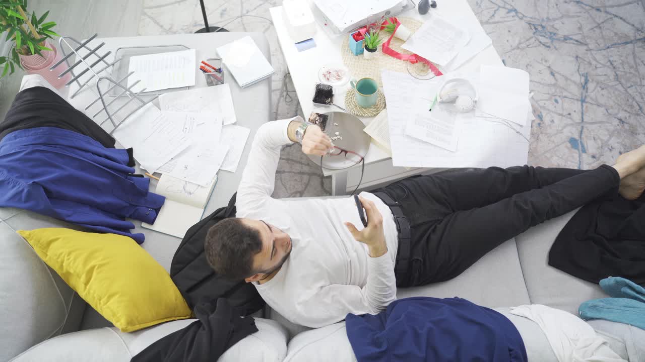 Tired lazy man lying on sofa in his untidy room.