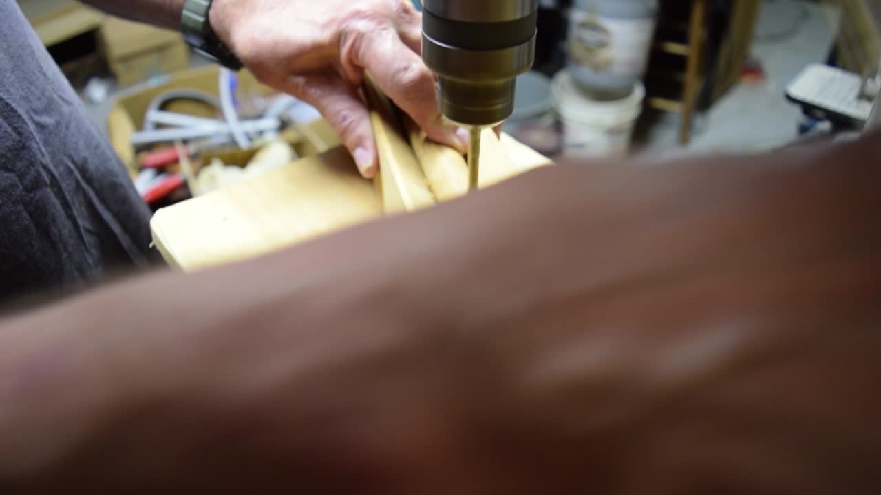 Man uses a drill press to drill a hole in a piece of wood.