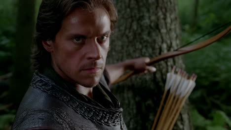 determined archer with bow and arrows in a forest